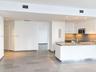 Modern kitchen featuring white flat-panel cabinetry, a central island with a solid-surface countertop, stainless steel appliances, and neutral-tone ti