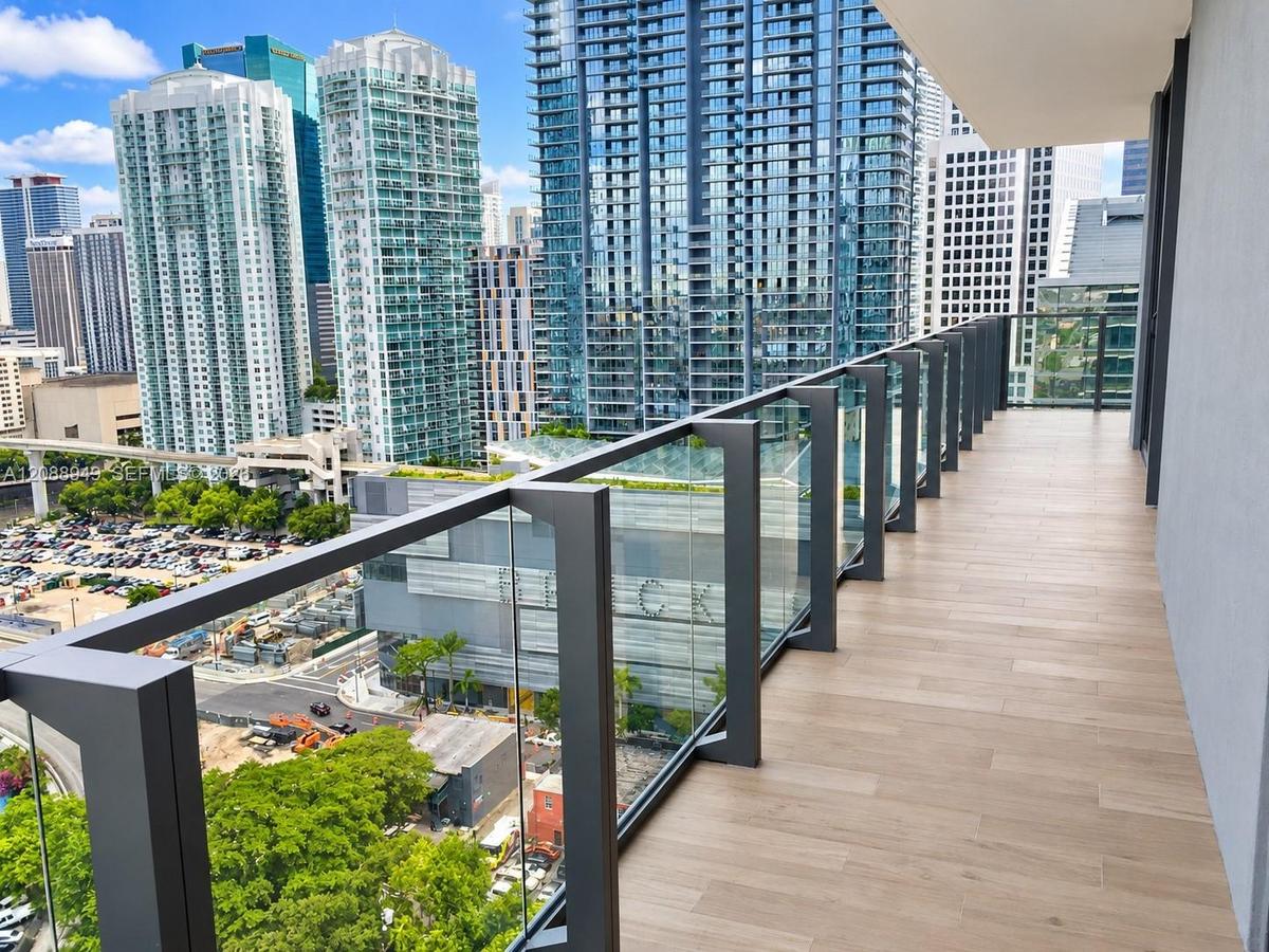 Private balcony featuring wood-finish flooring and a tempered glass railing with a dark metal frame