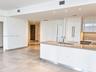 Modern kitchen featuring white flat-panel cabinetry, stone-finish countertops, recessed lighting, and large-format tile flooring