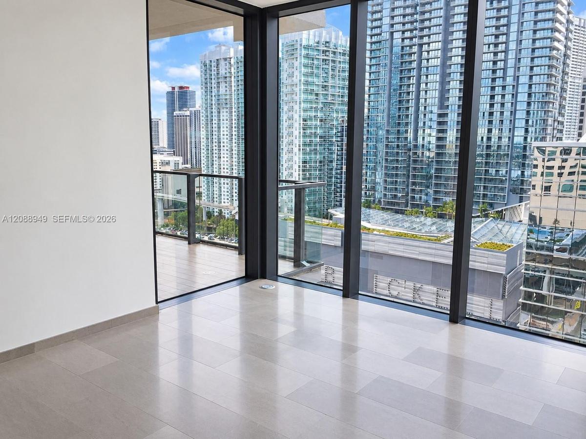 Floor-to-ceiling windows, large-format tile flooring, and private balcony with glass railing