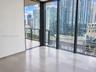 Floor-to-ceiling windows, large-format tile flooring, and private balcony with glass railing