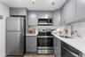 Kitchen featuring shaker-style cabinetry with metallic hardware, white solid-surface countertops, subway tile backsplash, and stainless steel applianc