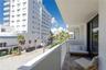 Private covered balcony featuring concrete flooring, a solid wall partition, and white metal railing