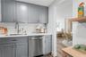 Kitchen featuring grey shaker-style cabinetry, white subway tile backsplash, solid-surface countertops, undermount stainless steel sink with pull-down