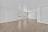 Open-concept interior featuring large-format tile flooring, recessed crown molding, dual windows, and a multi-arm chandelier