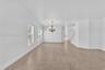 Large-format tile flooring, multi-light chandelier with metallic finish, crown molding, and staircase with white railings