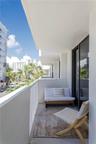 Covered balcony featuring white metal railings, concrete flooring, and sliding glass door access