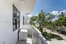Covered balcony with smooth concrete flooring, solid masonry privacy walls, and metal railings, featuring black-framed windows