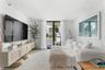 Living area featuring vertical plank wall paneling, a wall-mounted built-in console with cane detailing, and glass sliding doors leading to an exterio