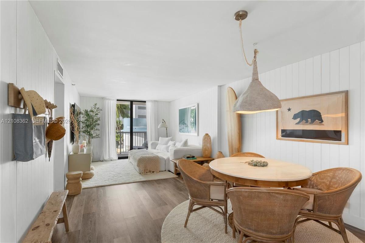 Vertical plank wall paneling, wood-finish flooring, and a large-format pendant light fixture with a corded suspension