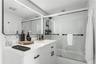 White vanity featuring a solid surface countertop, undermount sink, and matte black hardware, paired with a subway tile shower surround, sliding glass