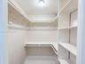 Walk-in closet featuring tiered wrap-around metal garment rods and custom built-in white shelving