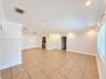 Open-concept interior featuring large-format ceramic tile flooring, neutral wall tones, recessed lighting, and multi-light pendant fixture