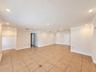 Open-concept room featuring large-format ceramic tile flooring with decorative inserts, recessed lighting, crown molding, and a multi-pendant light fi