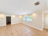 Neutral-toned tile flooring with decorative inserts, recessed lighting, crown molding, and large windows