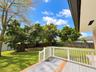 Backyard featuring a raised wooden deck with white railing, lawn area, and mature trees enclosed by a privacy fence