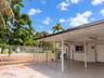 Covered carport with concrete flooring, exterior wall-mounted light fixture, and perimeter metal fencing
