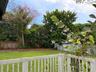 Rear yard featuring a grass lawn, perimeter wood fencing, and mature trees
