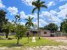 Single-story residence featuring a paved front walkway, decorative balustrade porch railing, exterior accent stone detailing, a brick-paved driveway, 