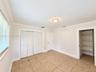Room featuring tile flooring, crown molding, a multi-panel door, built-in louvered-style closet doors, and a reach-in storage area with fixed shelving