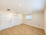Room featuring neutral tile flooring, recessed ceiling lighting, two sets of white louvered-style closet doors, and a single window with integrated bl