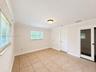 Neutral-toned interior space featuring tile flooring, crown molding, multi-pane windows, and a sliding glass panel door