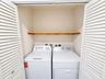 Laundry closet featuring white louvered doors and an installed wooden shelf
