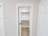 Walk-in closet featuring a sliding door, tiered white shelving, and tiled flooring