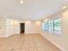 Neutral-toned tile flooring, recessed lighting, expansive multi-pane window with horizontal blinds, and crown molding