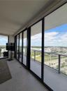 Floor-to-ceiling glass sliding doors, covered exterior balcony, stone-finish flooring, and metal railing