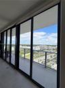 Floor-to-ceiling sliding glass panels, covered balcony with tile flooring, and metal-railing enclosure