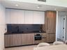 Modern kitchen featuring two-tone cabinetry with wood-finish lower cabinets, matte white upper cabinets, integrated refrigerator, stone backsplash, an