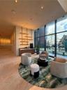 Floor-to-ceiling glass windows, recessed ceiling lighting, natural stone flooring, custom wall-mounted metal shelving, and a built-in wood-finish cred