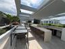 Rooftop terrace featuring a stone-topped built-in bar, integrated stainless steel grill, overhead pergola structure, and tiered concrete planters