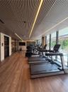 Slatted wood-finish ceiling with integrated linear LED lighting, wood-finish flooring, floor-to-ceiling glass windows, and glass-paneled entry door