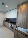 Kitchen featuring wood-finish cabinetry, matte black hardware, integrated appliance paneling, dark stone-finish countertops, and a stone-finish backsp