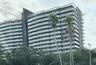 Modern high-rise exterior featuring a dark metallic facade, rhythmic rows of glass-railed balconies, and a stepped roofline