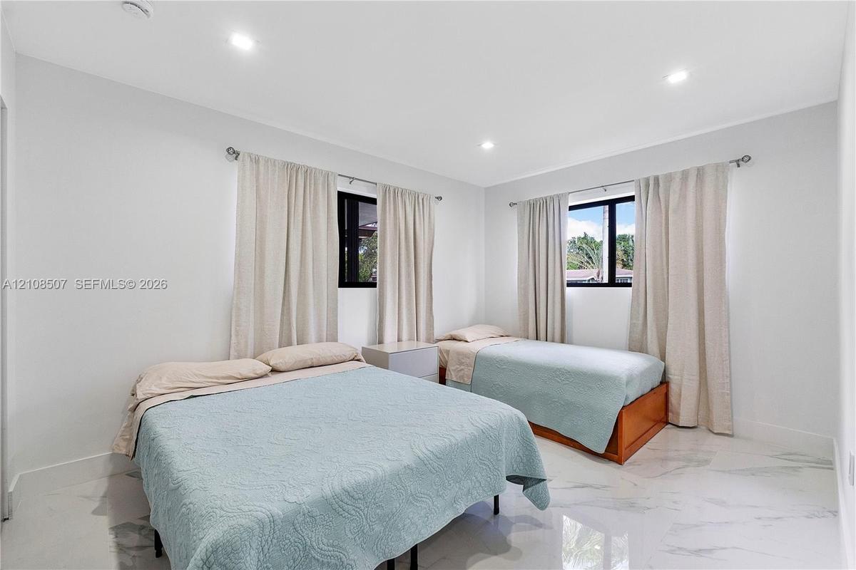 Neutral wall tones, polished stone-finish flooring, recessed ceiling lighting, and black-framed windows
