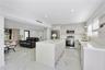 Kitchen featuring a central island with a solid-surface countertop, flat-panel cabinetry, stainless steel appliances, and large-format porcelain tile 