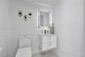 Floating white vanity with double drawers, metallic hardware, integrated stone countertop, LED-backlit mirror, and gold-finish faucet