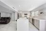 Kitchen featuring a stone-finish waterfall island, flat-panel cabinetry, stainless steel appliances, floating wall shelving, and large-format tile flo