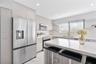 Kitchen featuring flat-panel cabinetry with gold-tone hardware, a central island with a solid-surface countertop, stainless steel appliances, and rece