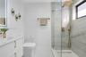 Bathroom featuring a white vanity with gold-tone hardware, large-format tiled walk-in shower with a rain-style showerhead, and matching gold-tone fixt