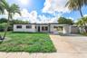 Single-story residence featuring a flat roofline, attached covered carport, decorative masonry screen wall, and concrete driveway