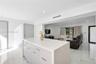 Center island featuring a white stone-surface countertop, recessed ceiling lighting, light-toned cabinetry with metallic hardware, and white tile floo