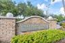 Brick entrance monument featuring a custom arch cap, spherical finials, and mature landscaping