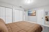 Room featuring wood-finish flooring, two sets of bifold closet doors, a solid-core interior door with matte black hardware, and a flush-mount ceiling 