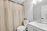 Bathroom featuring a white vanity cabinet with an integrated sink, polished chrome faucet, full-width mirror, and multi-bulb vanity lighting