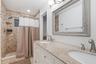 Dual-sink vanity featuring a light-toned stone countertop, recessed-panel cabinetry, and metal hardware