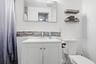 Bathroom featuring a white vanity cabinet with a integrated sink, metallic faucet, rectangular wall-mounted mirror, decorative horizontal mosaic tile 